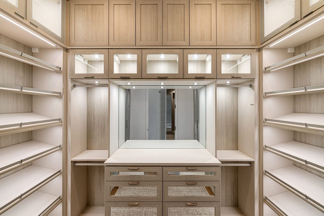 Spacious walk-in closet with wooden cabinets and ample lighting.